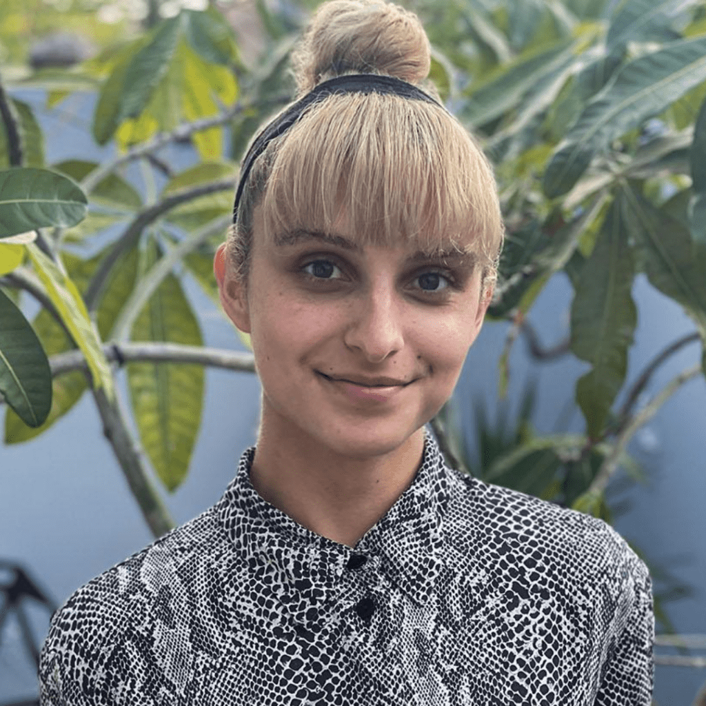 Headshot of Karina Domenech in front of some plants.