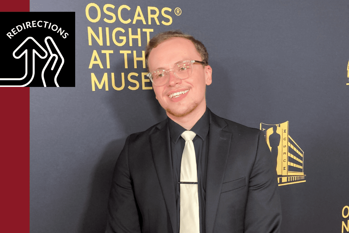 Hunter wears a suit and smiles in front of a wall that reads "Oscars night at the museum"